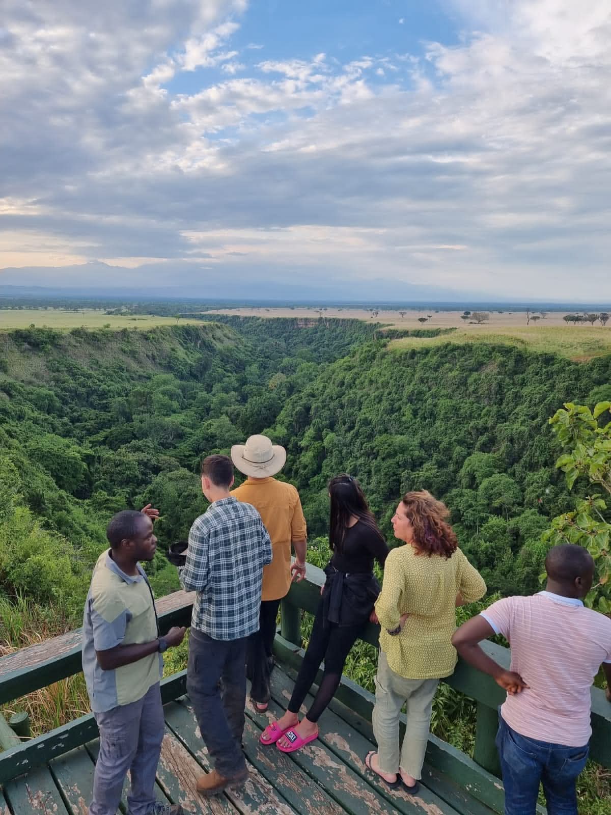 Group of guests standing on the viewing platform overlooking Kyambura Gorge in Queen Elizabeth National Park, preparing for chimpanzee tracking in Uganda.