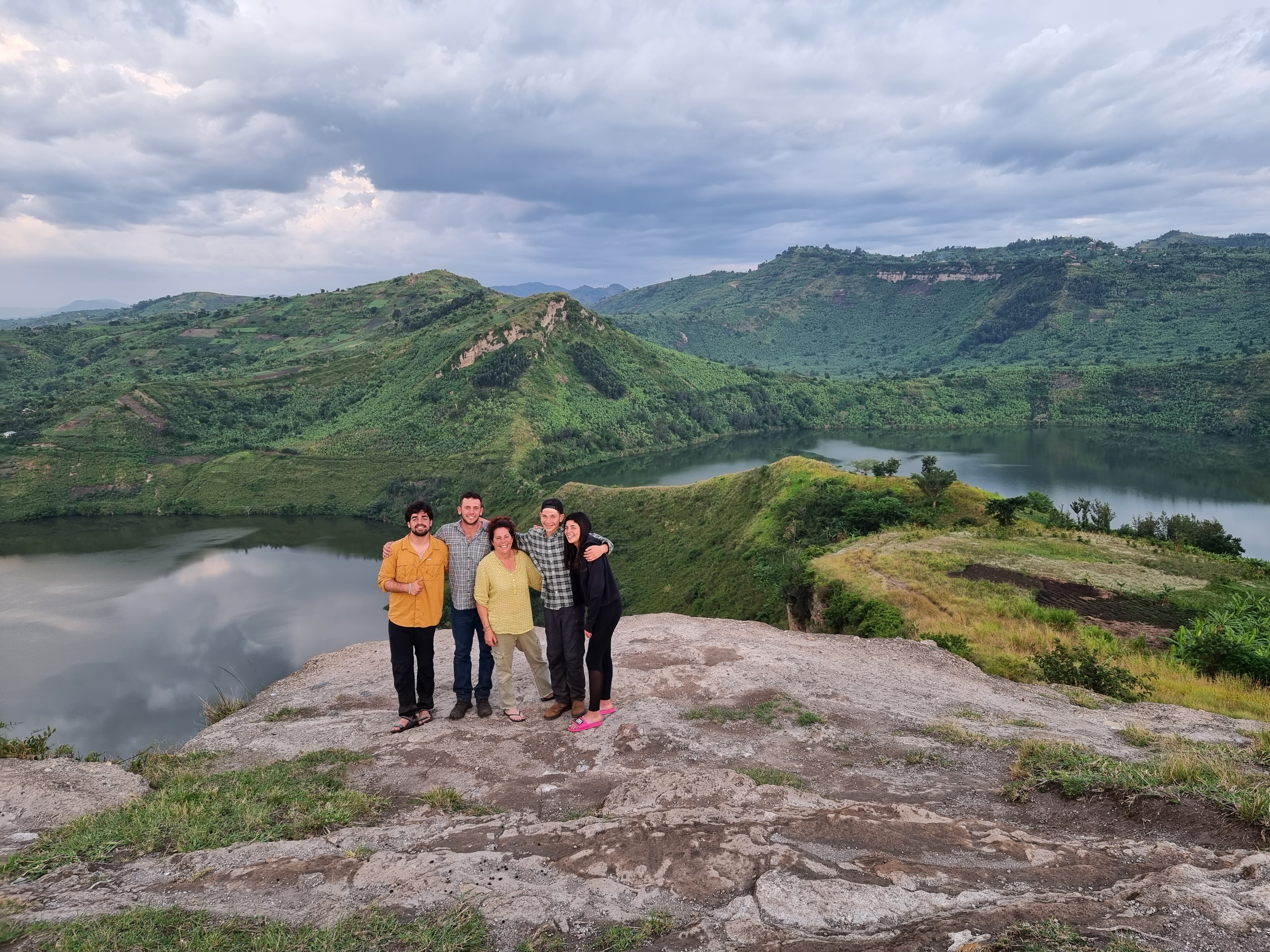A group of 5 clients standing and in the background are the twin lakes in Rubirizi, Uganda