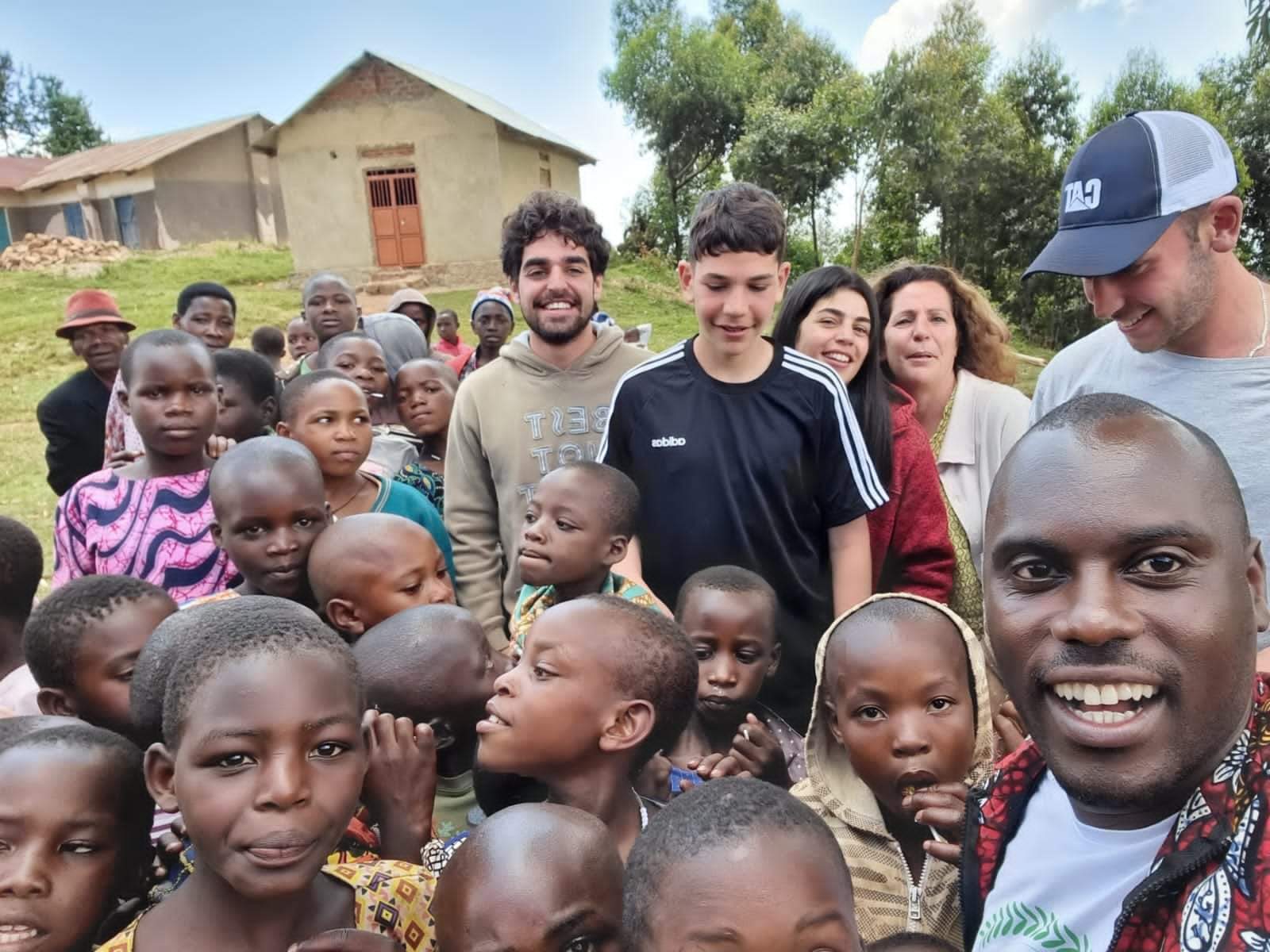 Small group of travelers posing for a photo with children during a community visit in Uganda